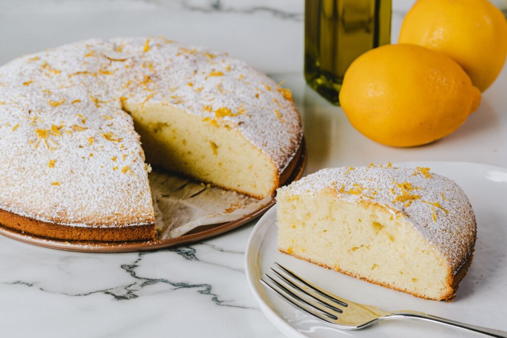 sliced round cake with lemons and an olive oil bottle in the background